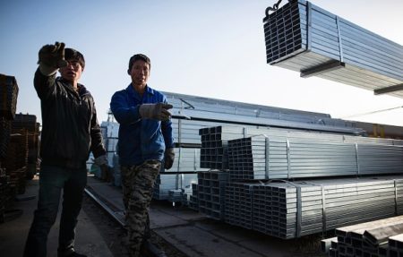 Workers carry steel tubing at a steel trading market in Beijing. (Emmanuel Wong/Getty Images)