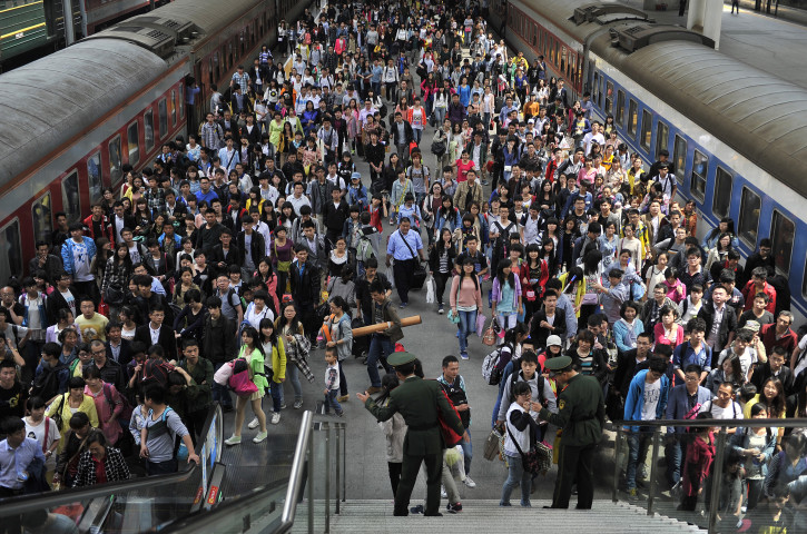 Paramilitary policemen direct passengers at a railway station during the traffic rush of the May Day holiday in Hefei