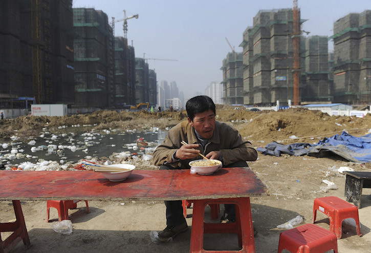 A migrant worker has his lunch near a construction site in Hefei